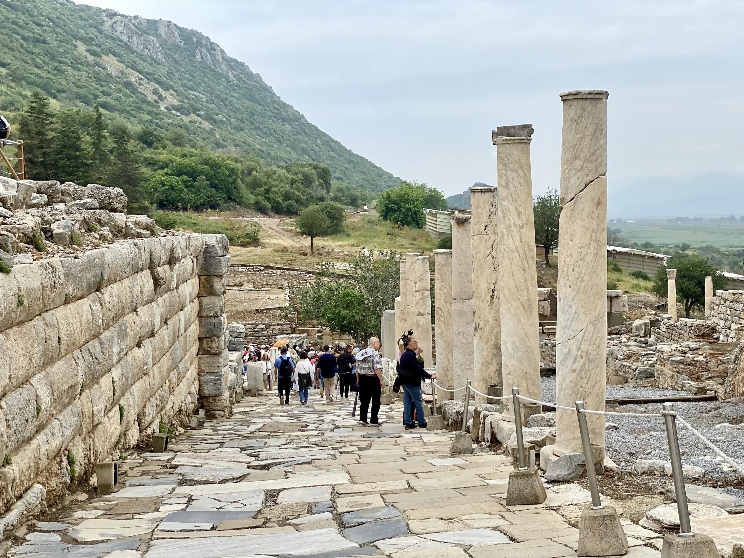 The colonnaded edge of Curetes Street, with standing columns, marble paving and the hills behind.